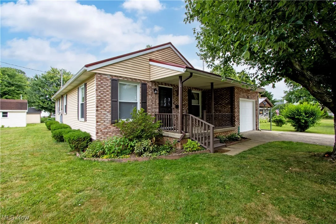 Single story home featuring driveway, brick siding, an attached garage, and a front lawn