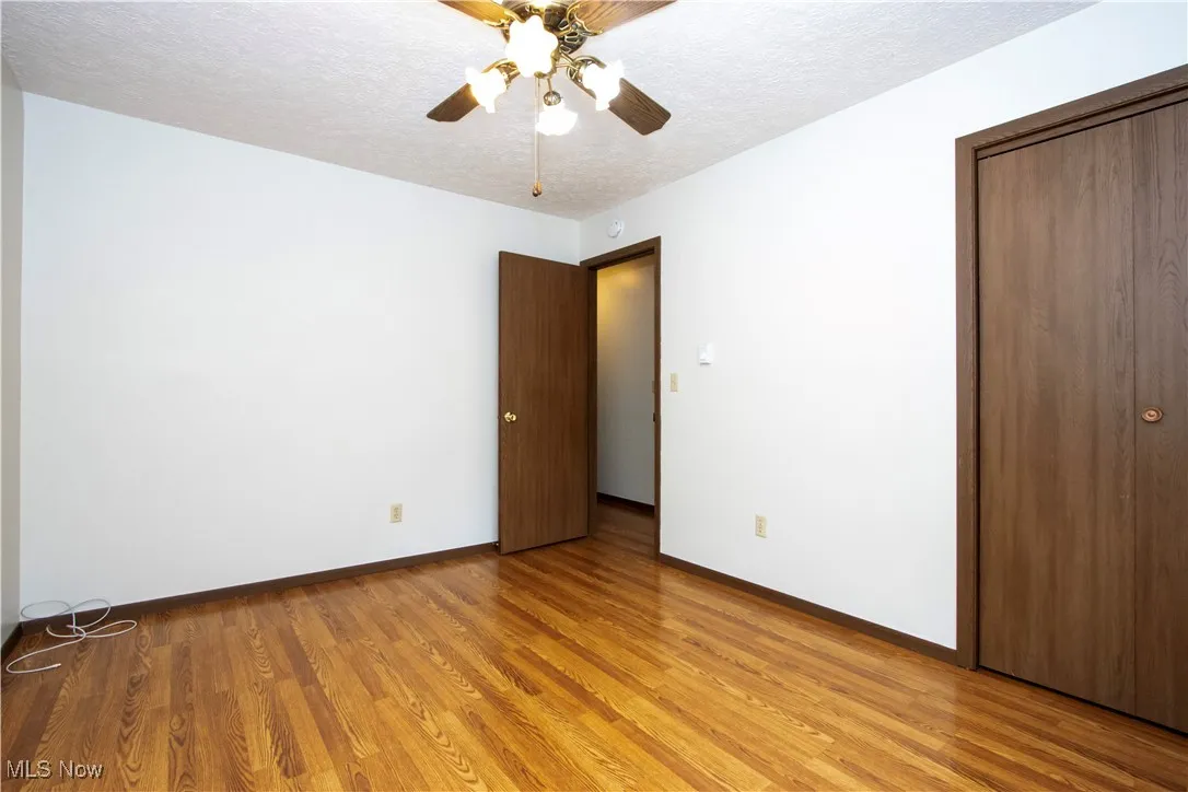 Unfurnished bedroom featuring light wood-type flooring, a textured ceiling, a closet, and ceiling fan