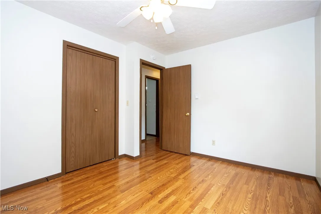 Unfurnished bedroom featuring light wood-style floors, a textured ceiling, a closet, and ceiling fan