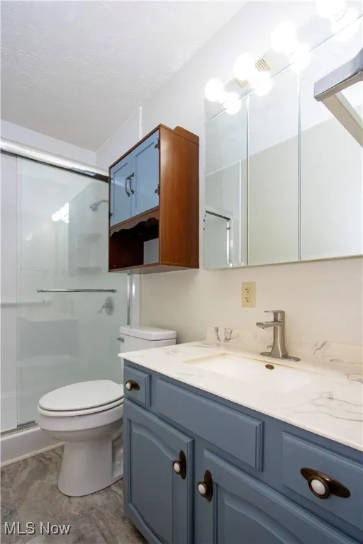 Bathroom with vanity, a shower stall, and a textured ceiling