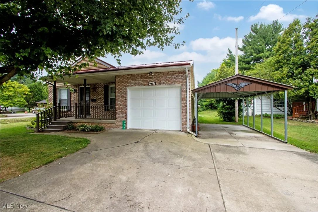 Ranch-style house featuring brick siding, a front lawn, concrete driveway, and a detached carport