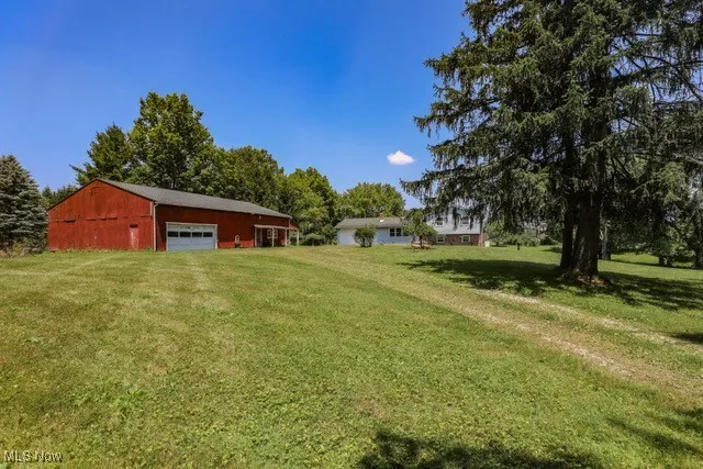 View of green lawn with a garage and an outbuilding
