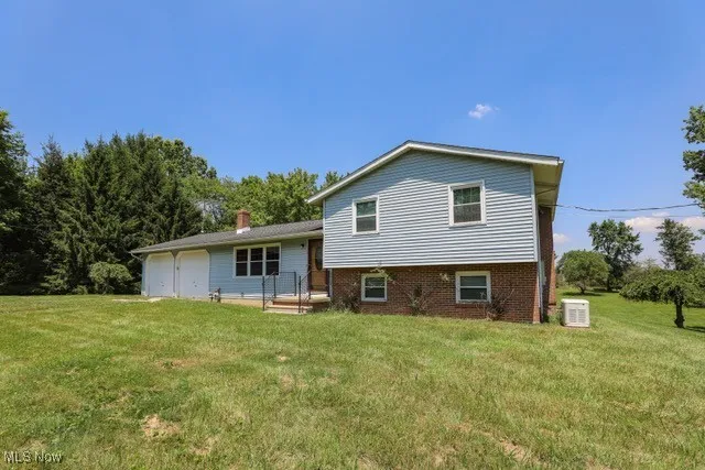 Rear view of property featuring a lawn and brick siding