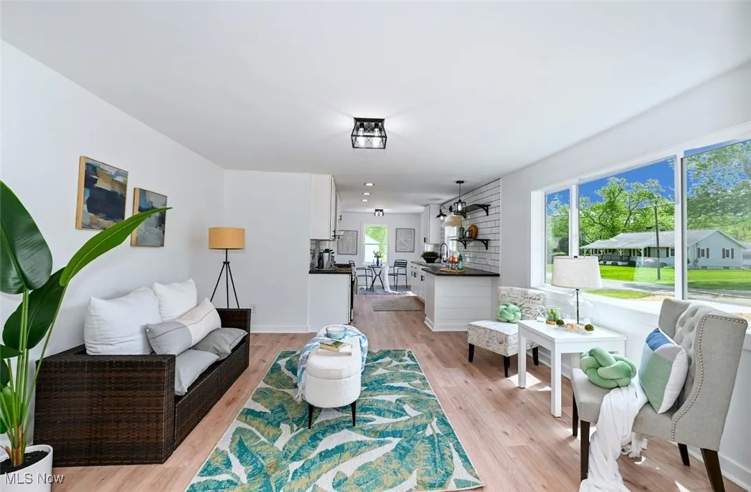 *LIVING RM W/LUXURY PLANK FLOORING, BLACK ACCENT CAGE LIGHTING & PICTURE WINDOW OPEN TO THE EAT IN KITCHEN ~