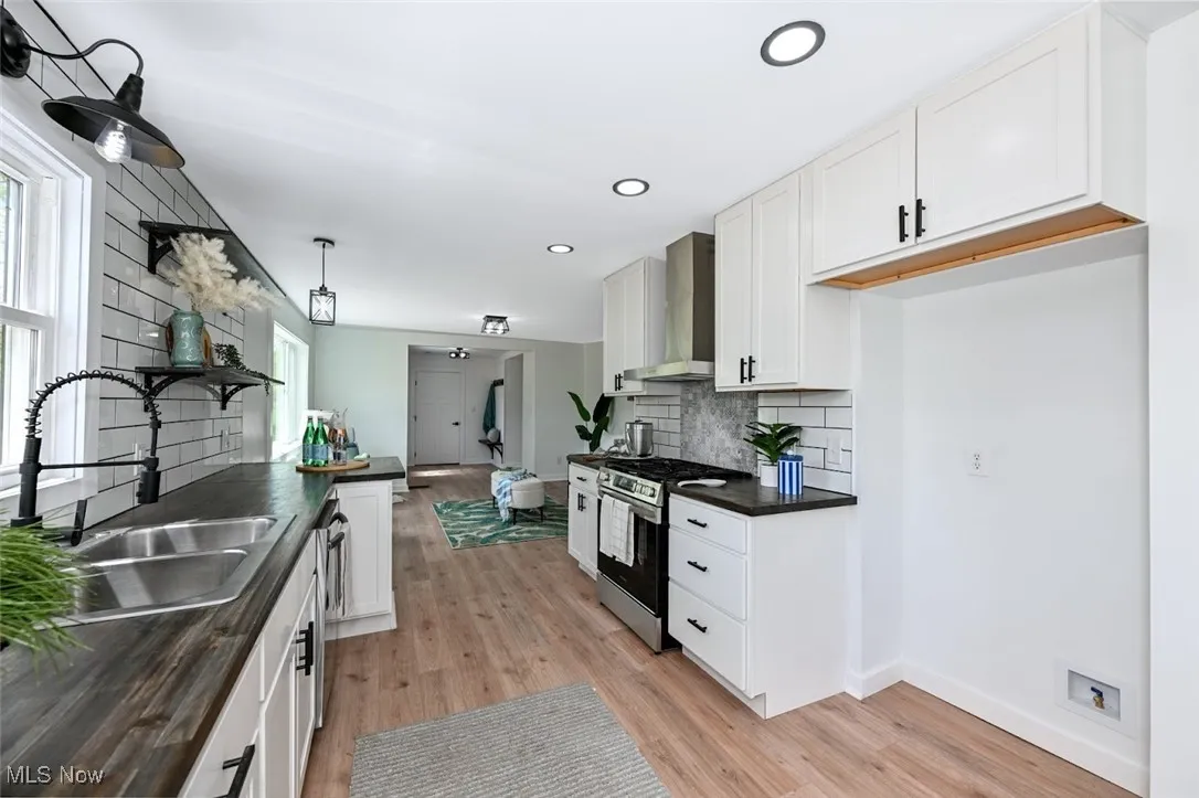 *KITCHEN W/RUSTIC BUTCHER BLOCK COUNTERTOPS, WALL SHELVING, SS SINK, BLACK COMMERCIAL STYLE FAUCET W/SPRAYER, NEW WHITE SHAKER CABINETS, WHITE SUBWAY TILE BACKSPLASH, SS DISHWASHER & SS OVEN W/MIDDLE GRIDDLE + HOOD SYSTEM CUSTOM TILED ABOVE RANGE ACCENT AND MORE! ~