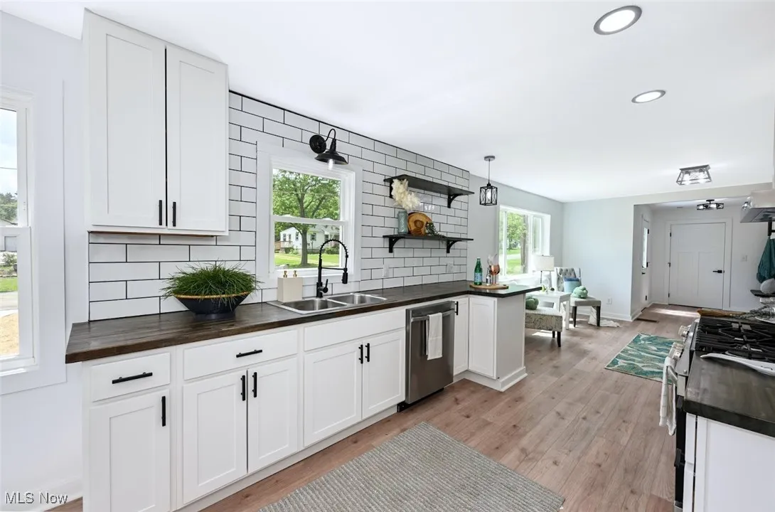 *KITCHEN W/RUSTIC BUTCHER BLOCK COUNTERTOPS, WALL SHELVING, SS SINK, BLACK COMMERCIAL STYLE FAUCET W/SPRAYER, NEW WHITE SHAKER CABINETS, WHITE SUBWAY TILE BACKSPLASH, SS DISHWASHER & SS OVEN W/MIDDLE GRIDDLE + HOOD SYSTEM CUSTOM TILED ABOVE RANGE ACCENT AND MORE! ~