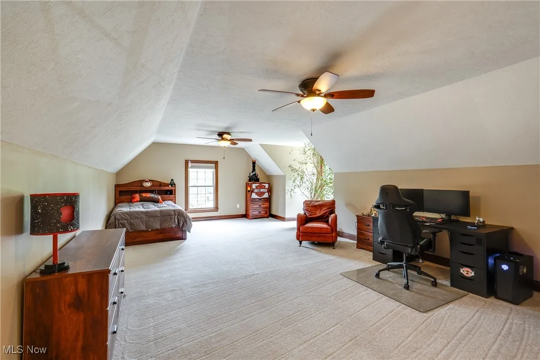 Bedroom with carpet flooring, a textured ceiling, lofted ceiling, an office area, and ceiling fan