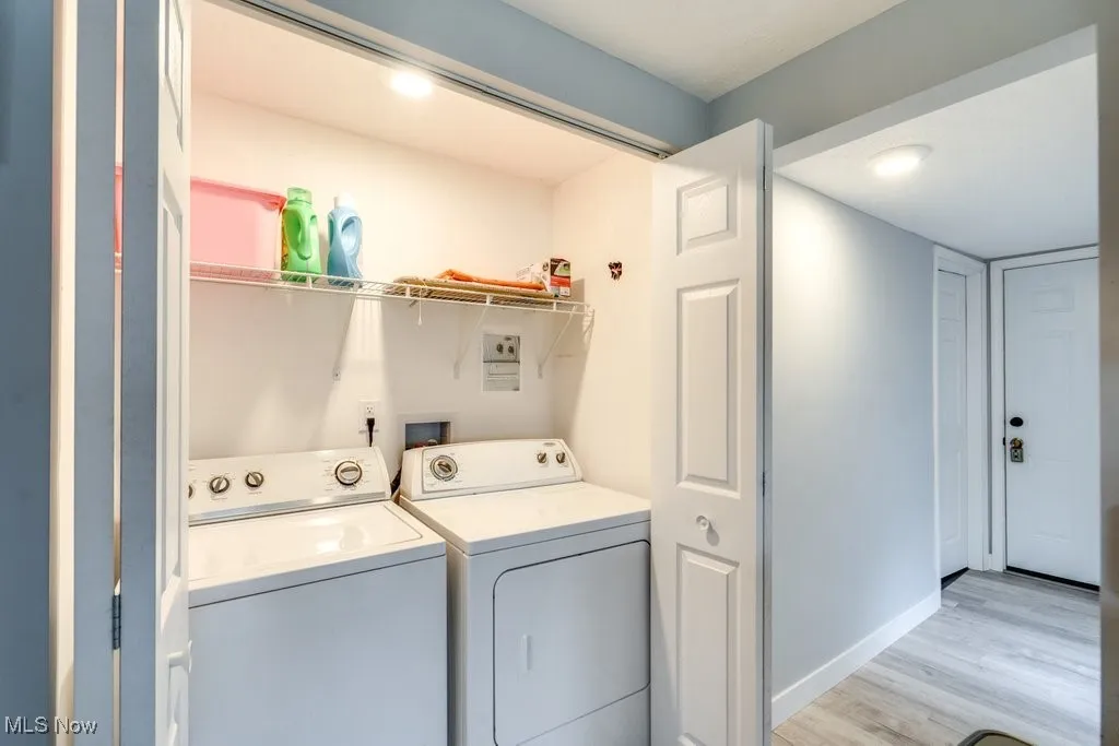 Laundry area with laundry area, baseboards, washing machine and dryer, and light wood-style floors
