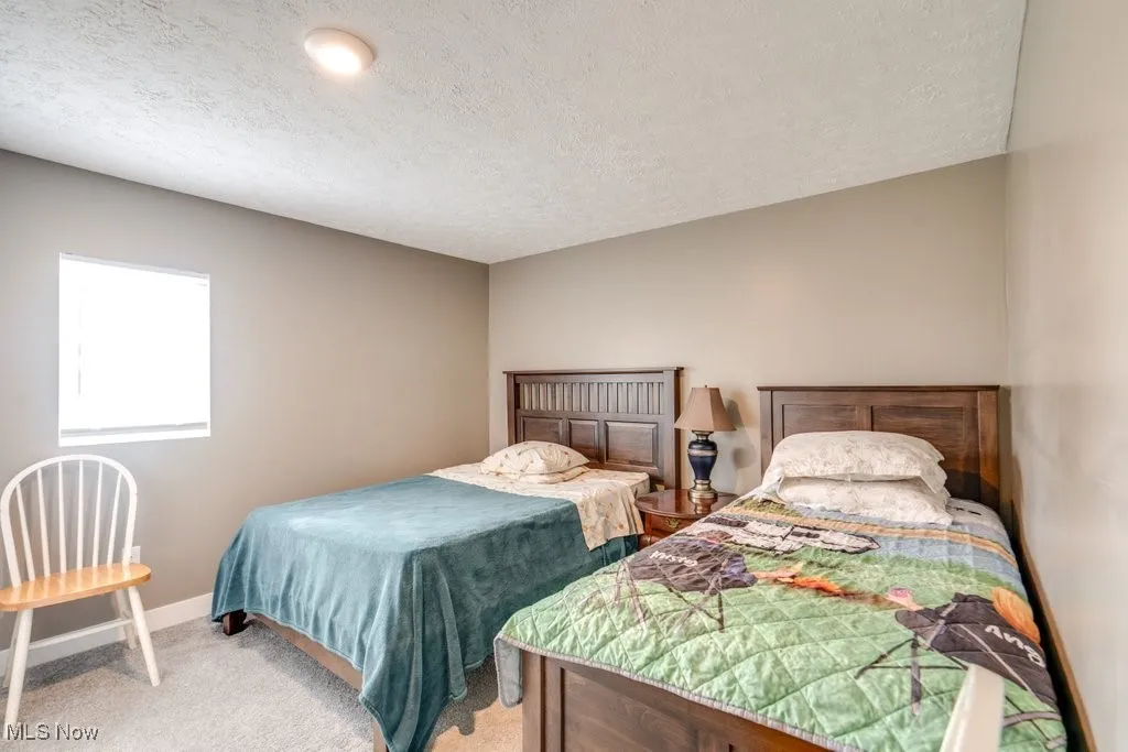 Carpeted bedroom with baseboards and a textured ceiling