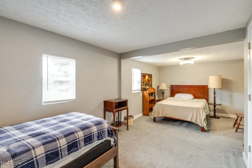 Bedroom with a textured ceiling, carpet flooring, and baseboards