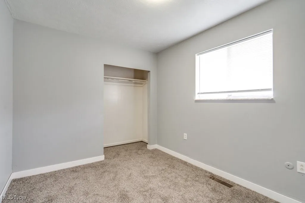 Unfurnished bedroom with visible vents, baseboards, a closet, and carpet