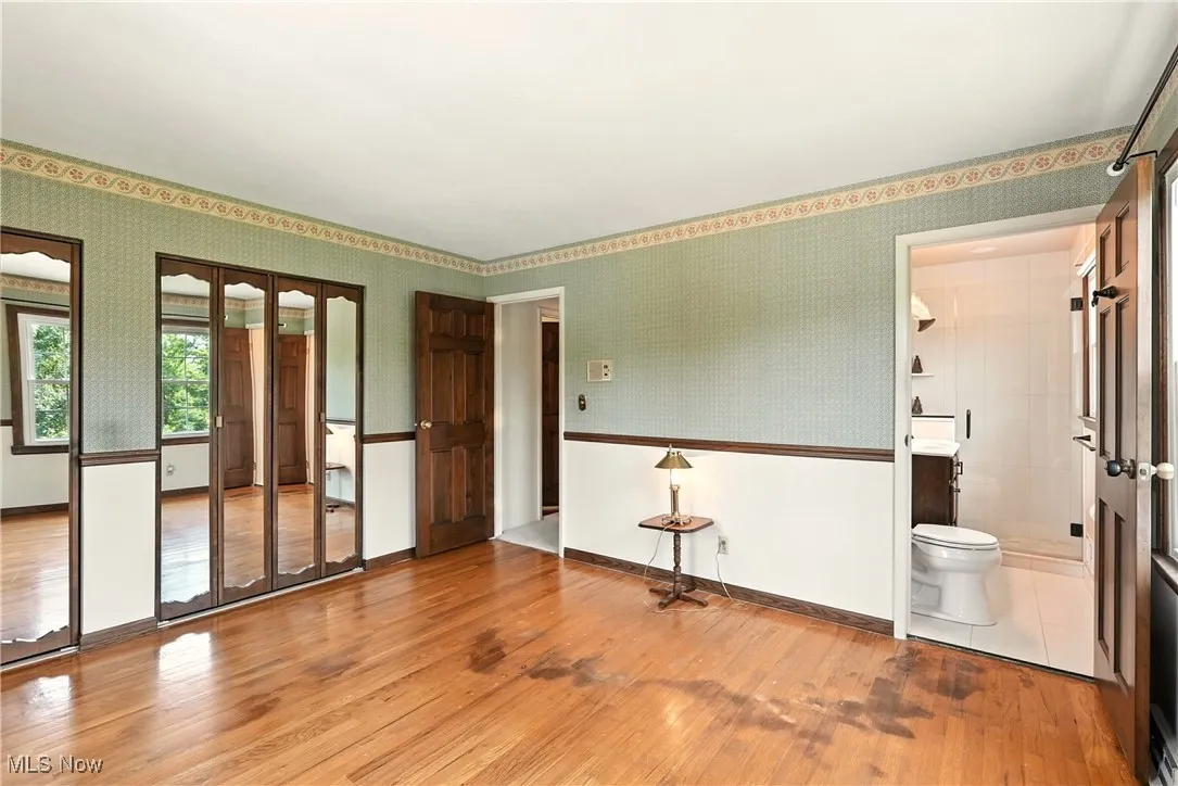 Unfurnished room with wallpapered walls and wood finished floors