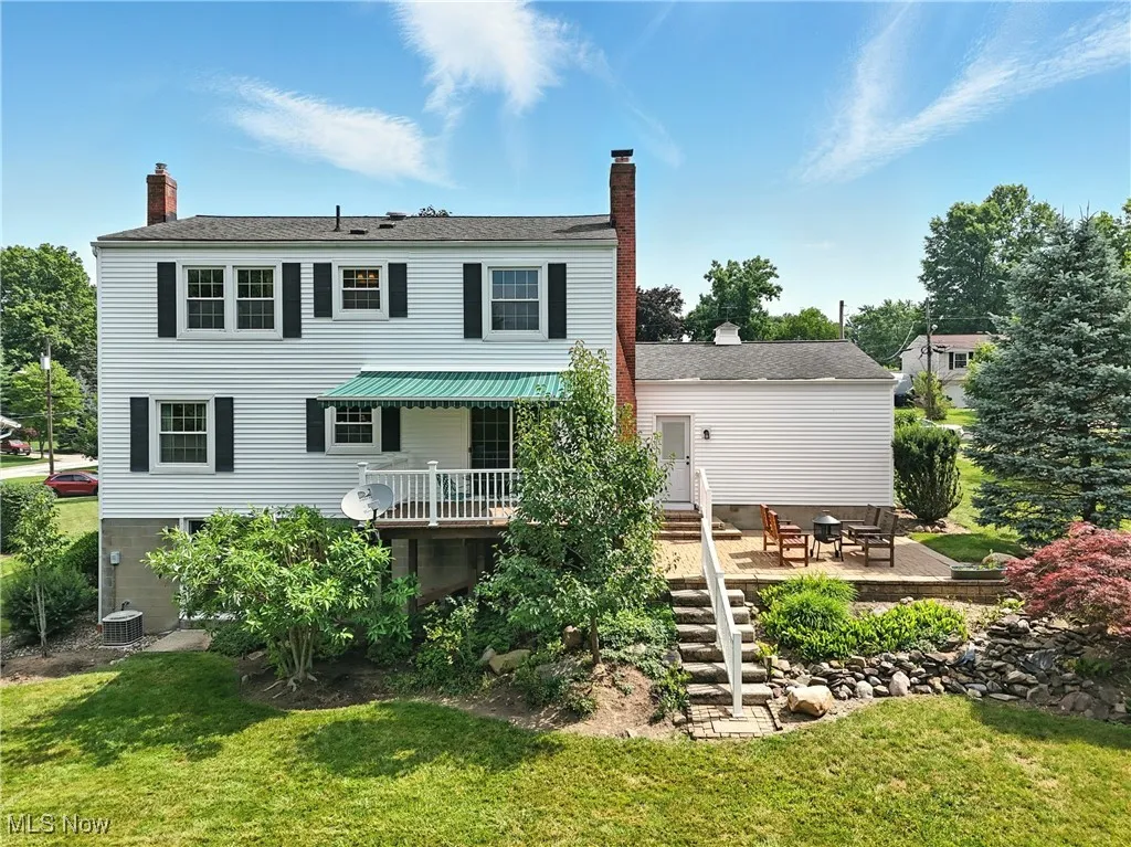 Back of house with a chimney, a lawn, and a deck