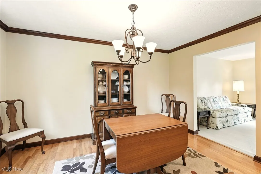 Dining space with a chandelier, light wood-style flooring, and ornamental molding