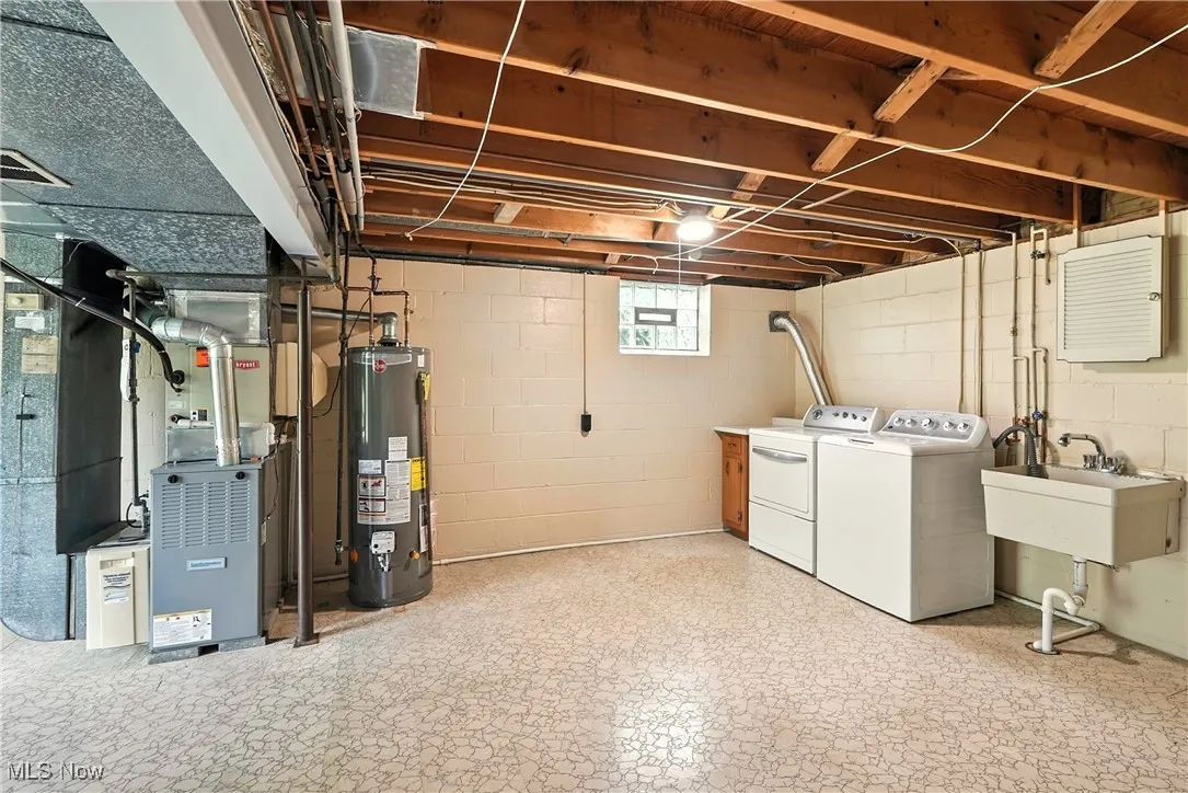 Below grade area featuring gas water heater, washer and dryer, and heating unit
