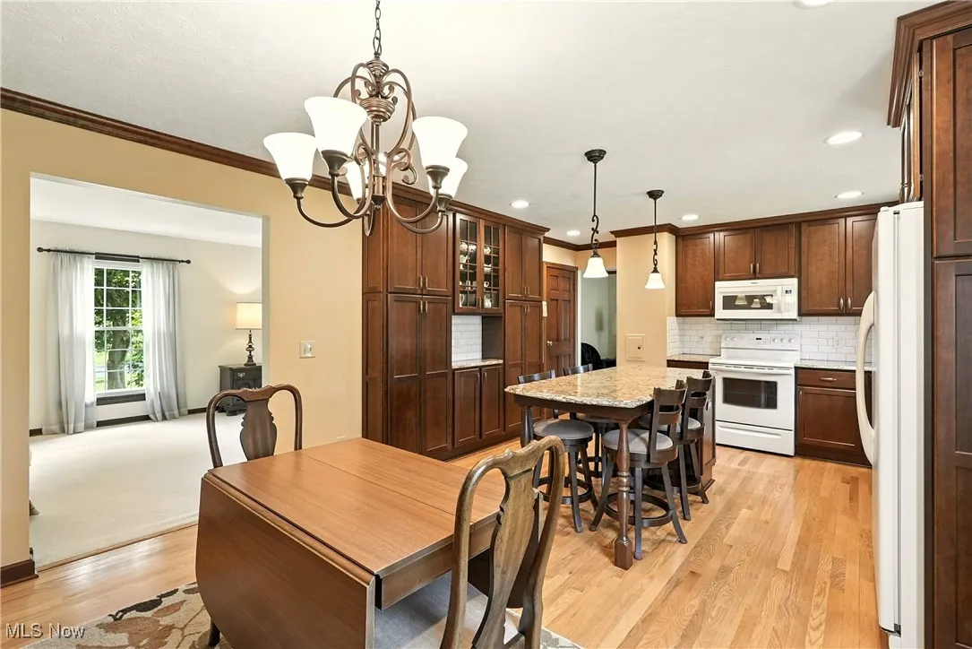 Dining room with ornamental molding, light wood-type flooring, a chandelier, and recessed lighting