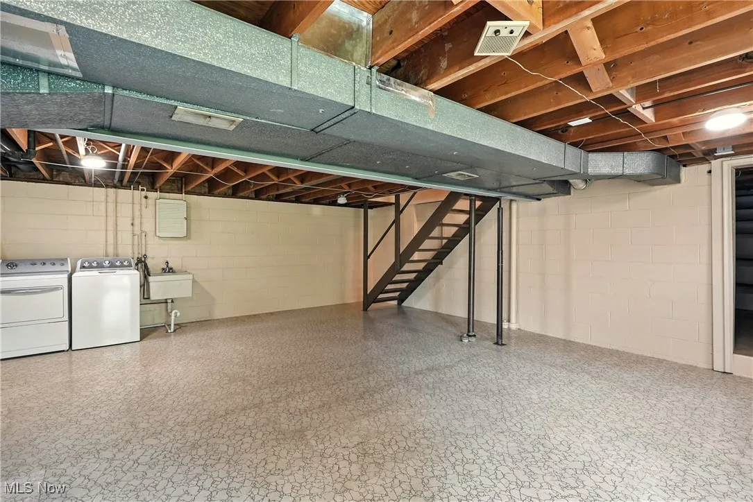 Unfinished basement featuring stairway and separate washer and dryer