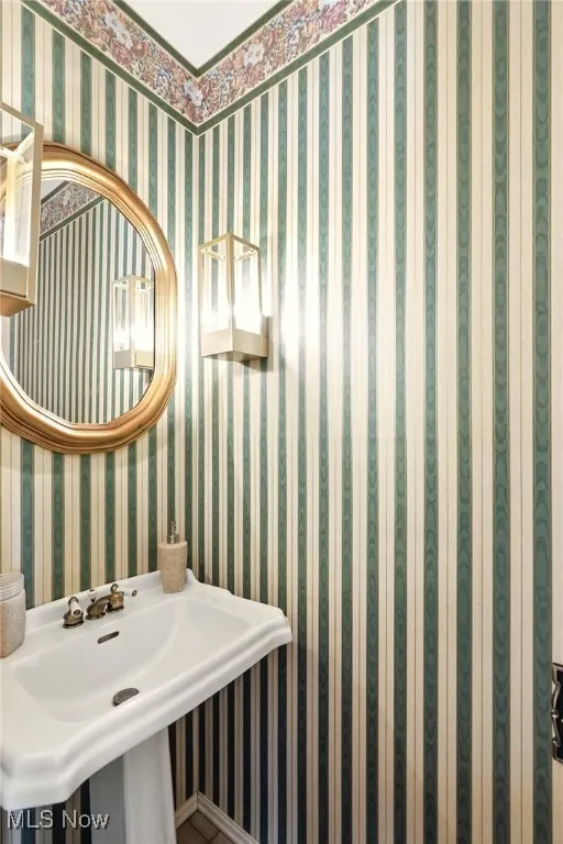 Bathroom with wallpapered walls and a sink
