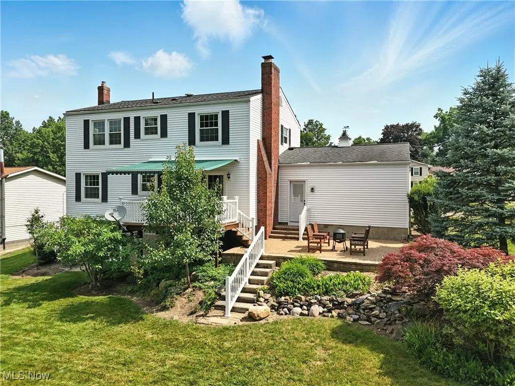 Rear view of house featuring a lawn, a chimney, a patio area, and entry steps