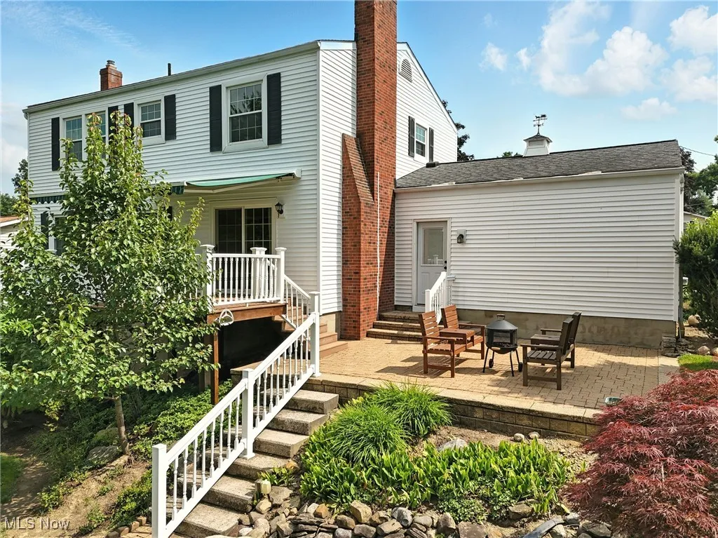 Back of house featuring a chimney, a patio area, entry steps, and a wooden deck
