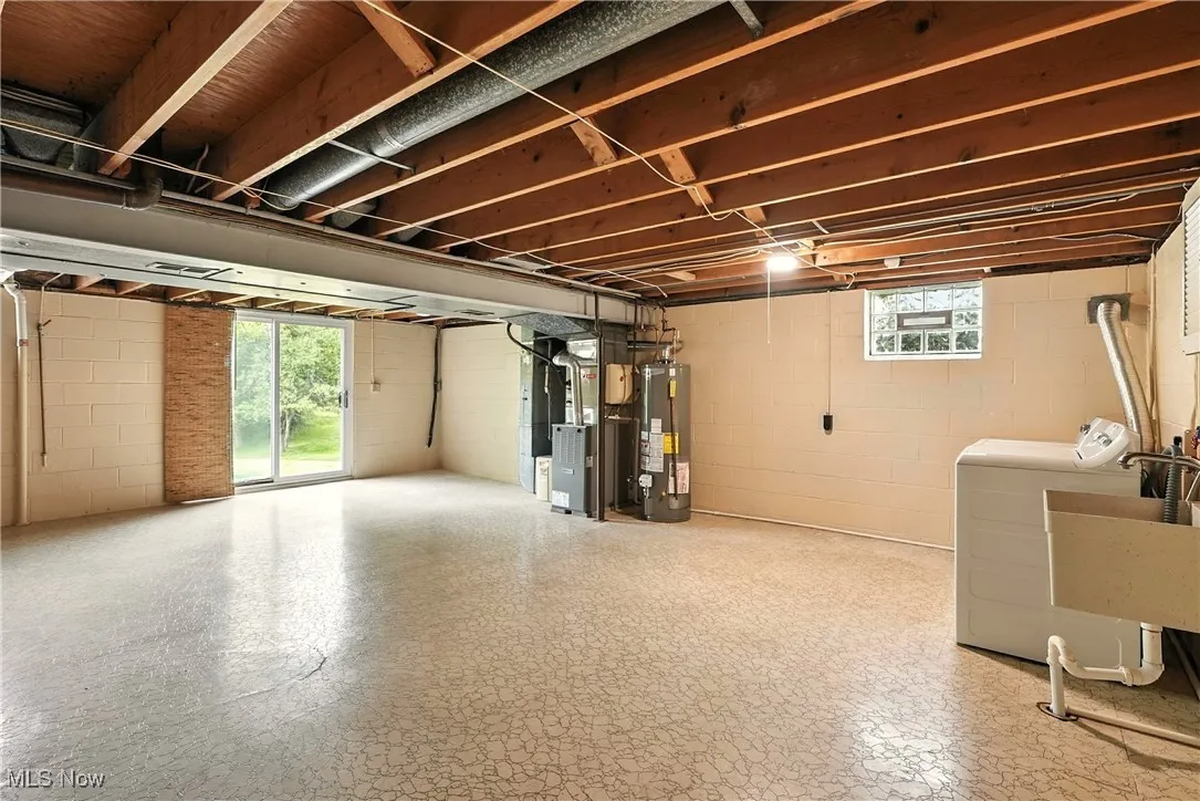 Below grade area with washer and clothes dryer, water heater, and concrete block wall