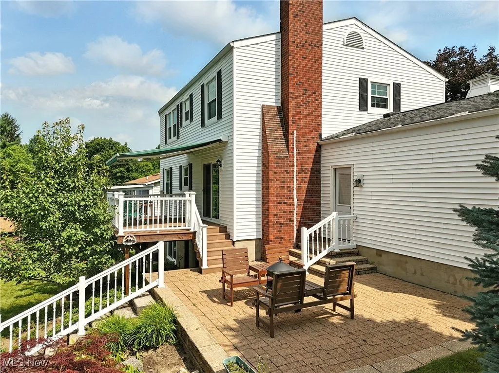 Rear view of property featuring stairs, a patio area, a chimney, and a wooden deck