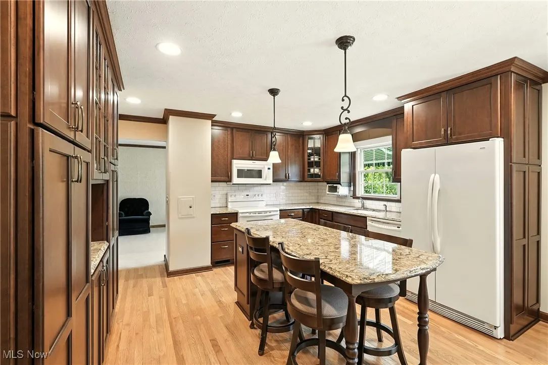 Kitchen featuring white appliances, tasteful backsplash, ornamental molding, light wood-style flooring, and recessed lighting