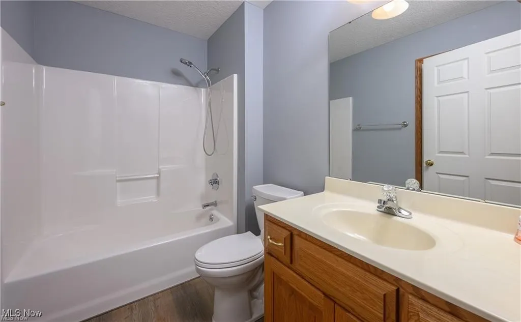 Bathroom featuring a textured ceiling, wood finished floors, vanity, and shower / tub combination
