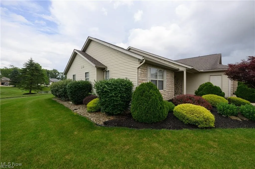 View of property exterior with stone siding and a lawn