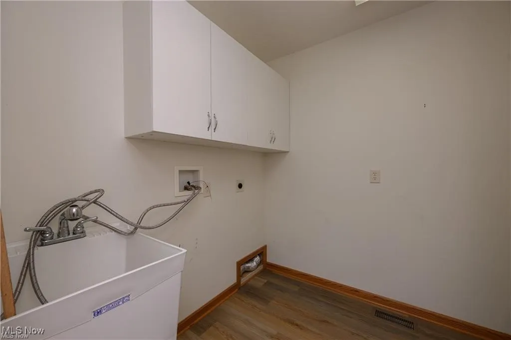 Laundry area featuring electric dryer hookup, cabinet space, wood finished floors, and hookup for a washing machine