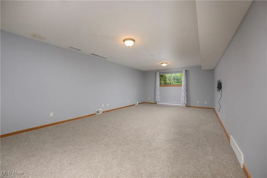 Empty room with light colored carpet and baseboards