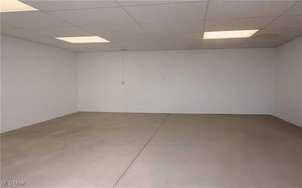 Basement with concrete block wall and a paneled ceiling
