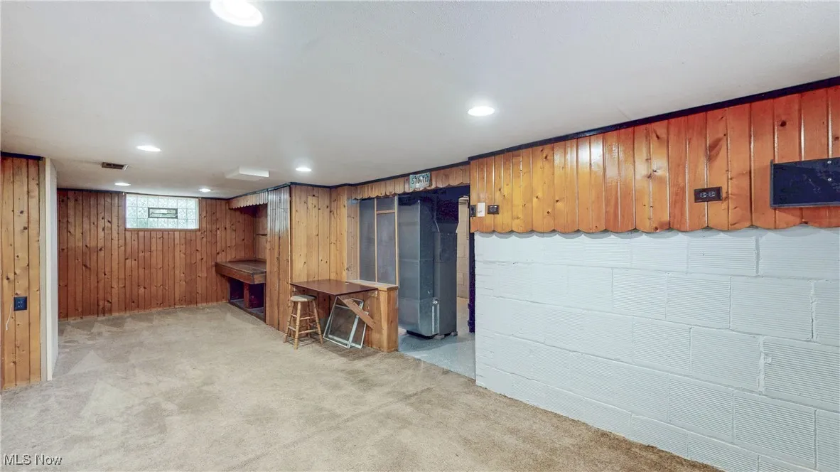 Below grade area featuring carpet, recessed lighting, and wooden walls