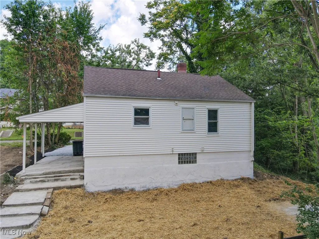 View of side of home with a shingled roof and a chimney