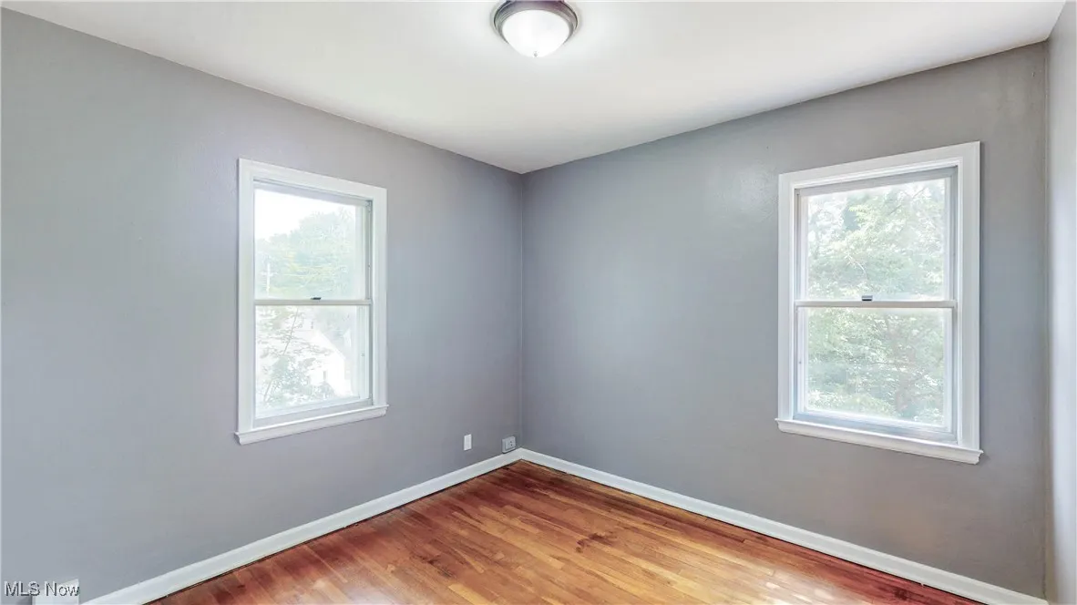 Spare room with baseboards and wood finished floors