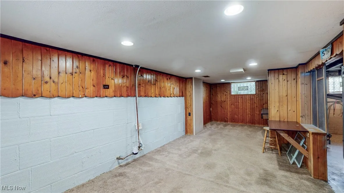 Basement with light carpet, wooden walls, and recessed lighting