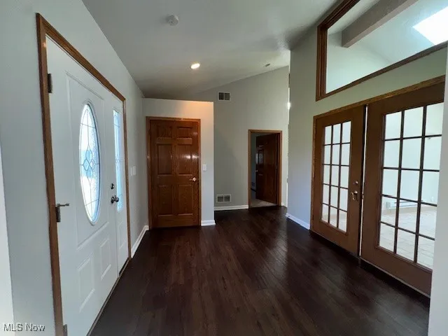 Foyer with dark wood-style floors, french doors, and recessed lighting
