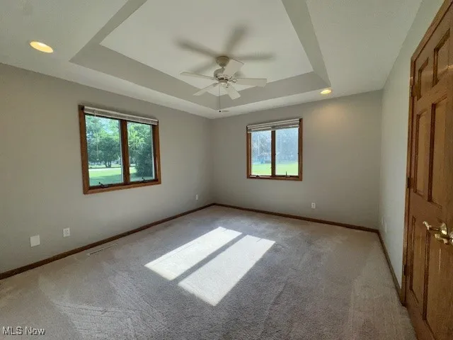 Spare room with a raised ceiling, ceiling fan, light colored carpet, and recessed lighting