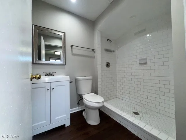 Full bathroom with vanity, wood finished floors, and a tile shower