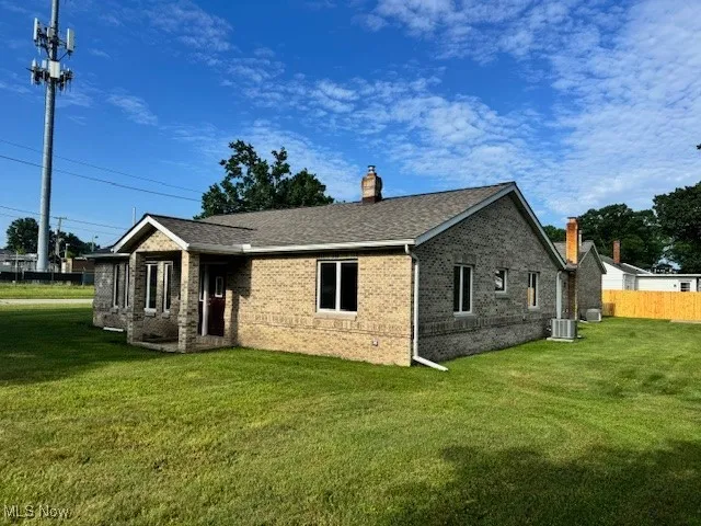 Side view of property with a chimney, brick siding, and roof with shingles
