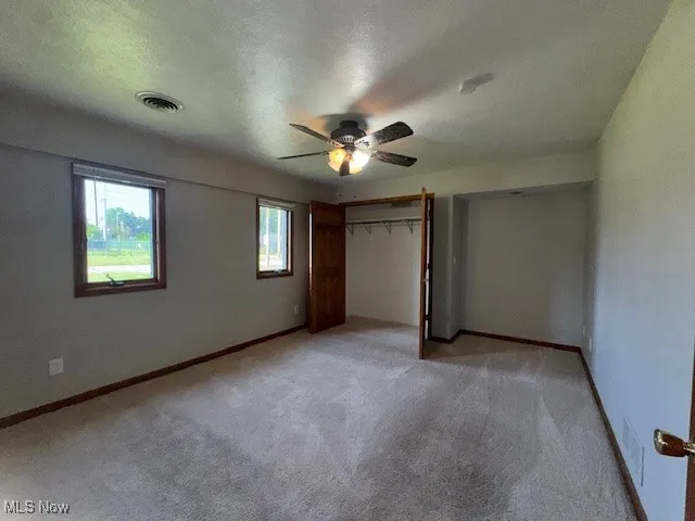 Unfurnished bedroom with light carpet and a ceiling fan