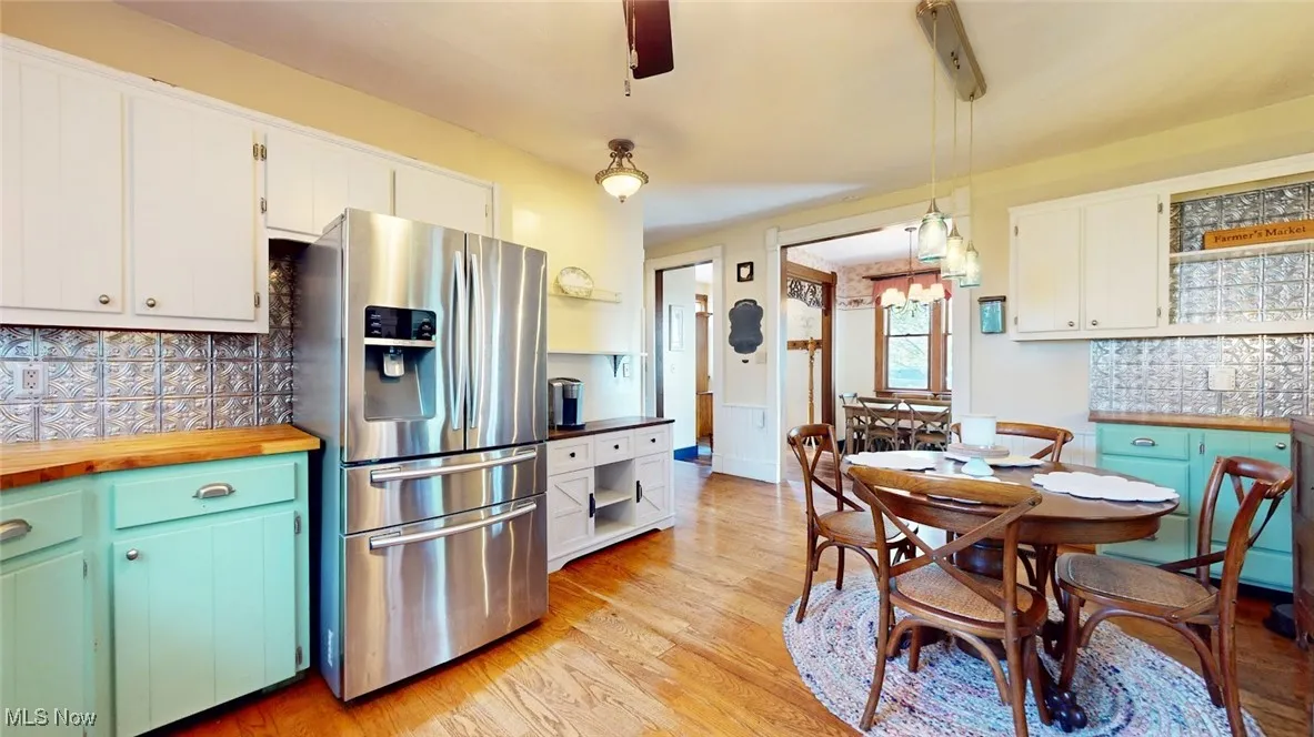 Kitchen with stainless steel fridge with ice dispenser, tasteful backsplash, and white cabinetry