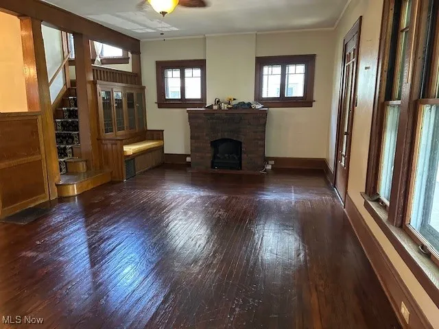 Unfurnished living room with wood-type flooring, a fireplace, ornamental molding, and plenty of natural light