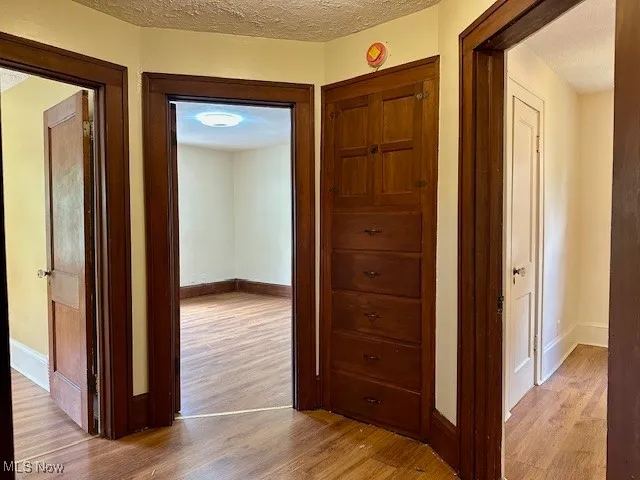 Hall featuring light wood-style floors and a textured ceiling
