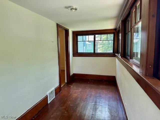 Unfurnished room with dark wood-style flooring and baseboards