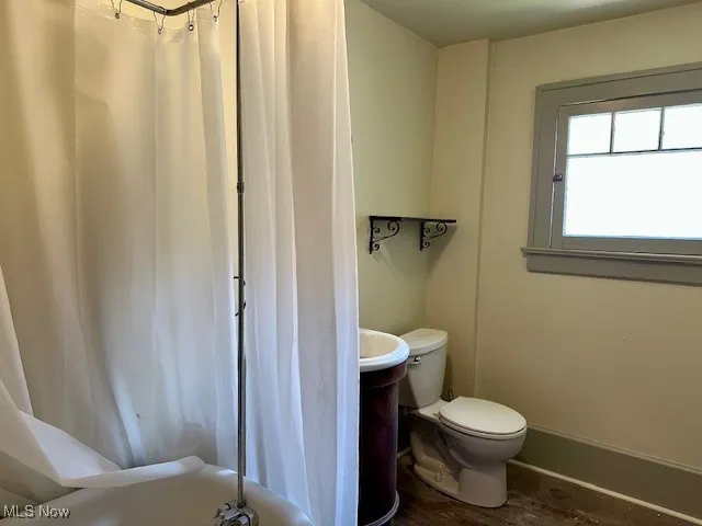 Full bath featuring toilet and wood finished floors