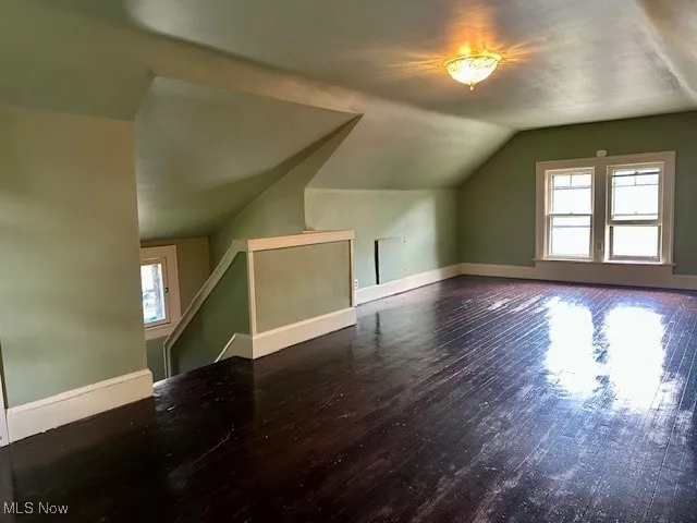 Additional living space with wood finished floors, plenty of natural light, and vaulted ceiling