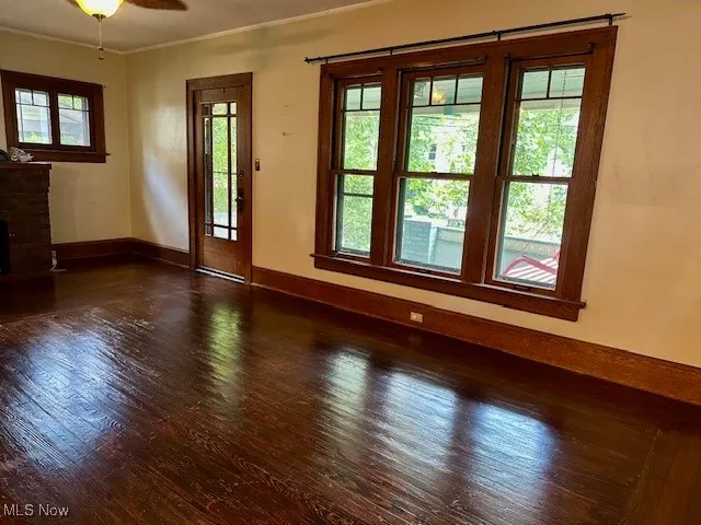Unfurnished room with hardwood / wood-style floors, ornamental molding, healthy amount of natural light, and a fireplace