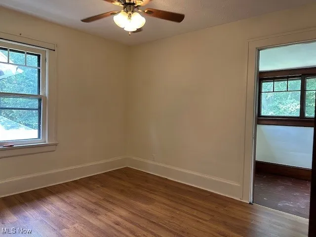 Spare room featuring dark wood-style floors and ceiling fan