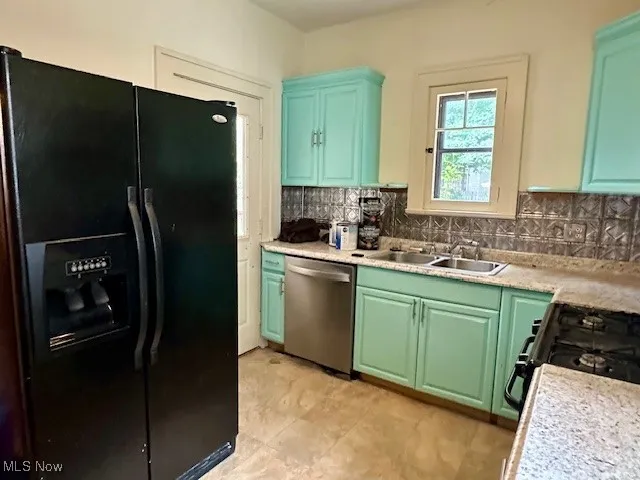 Kitchen with black appliances, light countertops, and tasteful backsplash